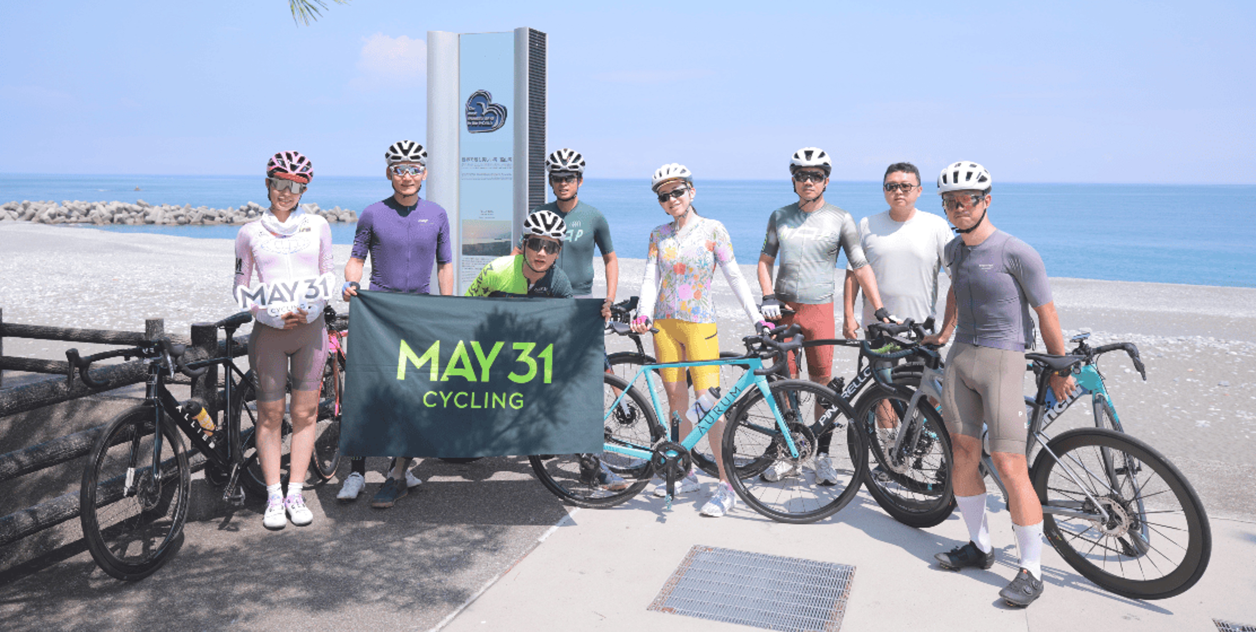 Cyclists with MAY31 banner on a coastal road